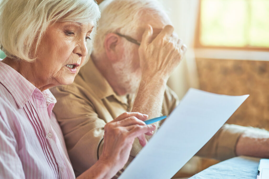 Two seniors going over their finances and struggling, a sign that they may need the help of daily money managers for seniors.