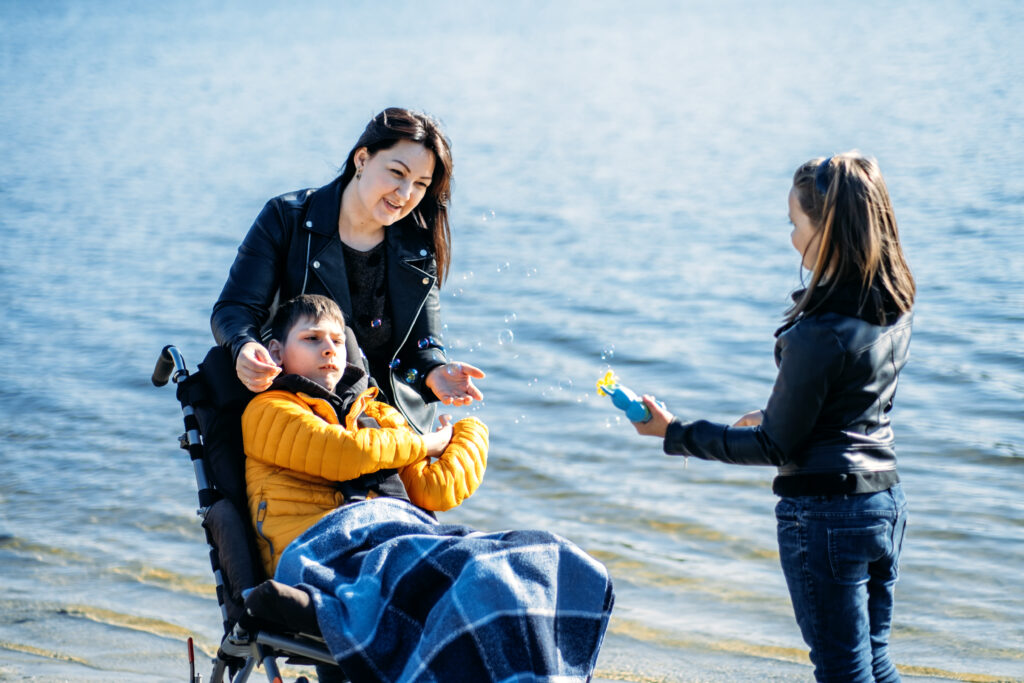 A family with a special needs loved one at the beach, providing them with a great quality of life and a fitting analogy for why it’s crucial to use this tool and understand the answer to the question, What can a special needs trust pay for in California?
